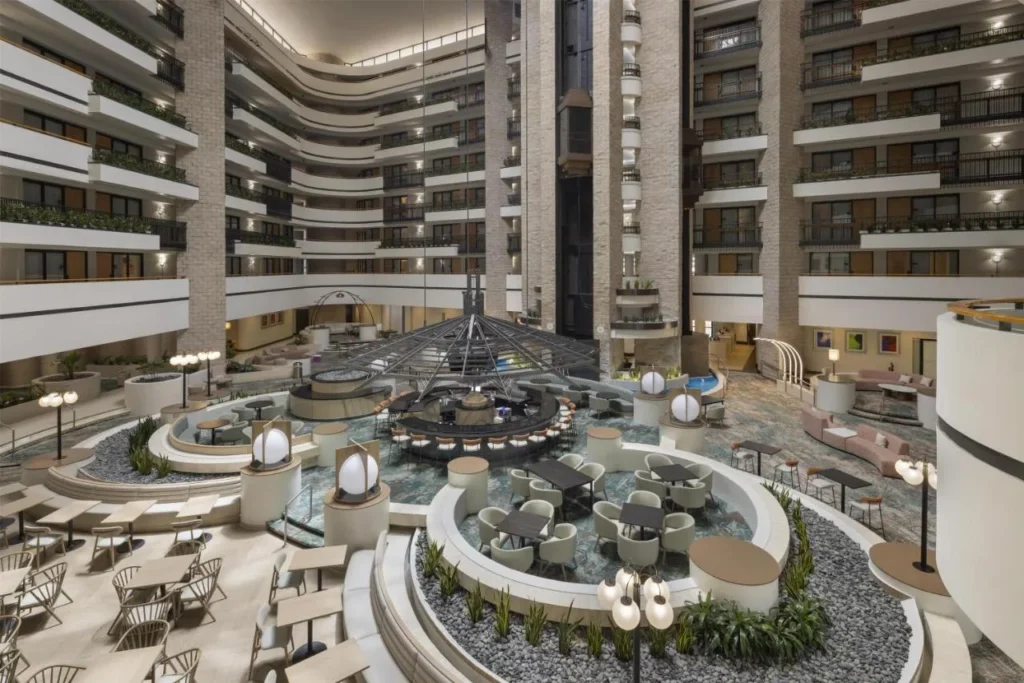 Atrio renovado con barra central y asientos debajo de los balcones en Embassy Suites ICON Park