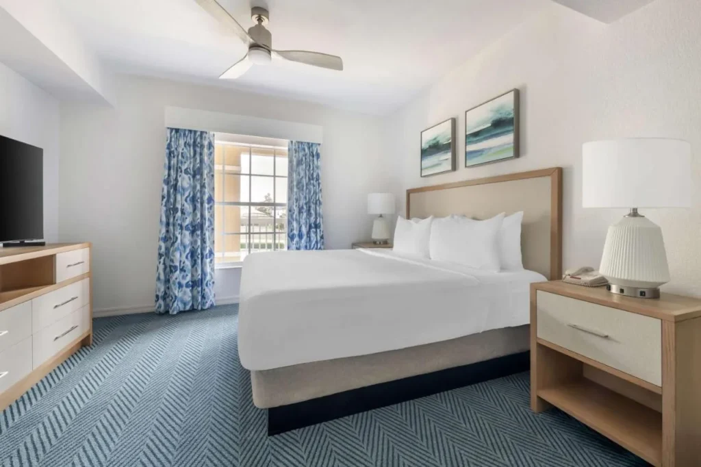 Dormitorio renovado con una cama grande, alfombra de espiga y ventilador de techo en Mystic Dunes Resort