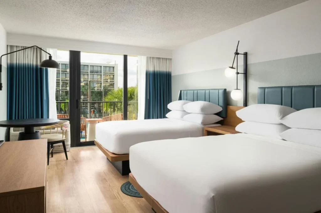 Habitaci&oacute;n renovada con dos camas, piso de madera y puerta de balc&oacute;n en Sheraton Lake Buena Vista