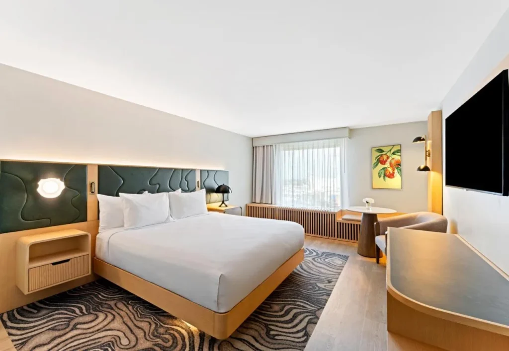 Renovated king room with sitting area and light wood furniture at Rosen Plaza Hotel