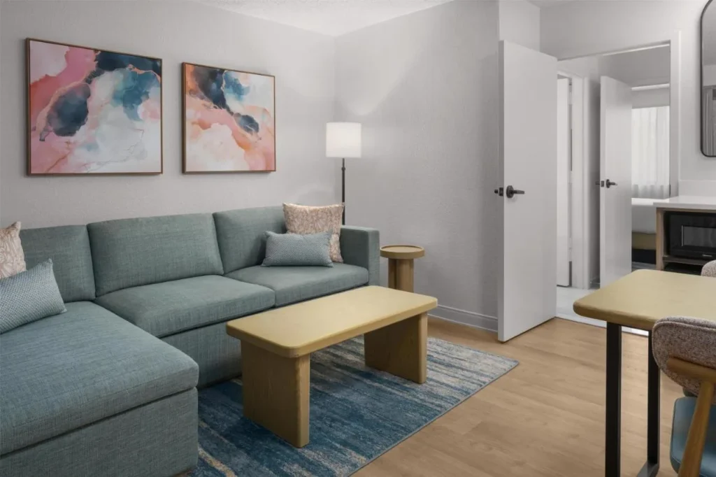 Renovated suite living room with sectional sofa and bedroom door at Embassy Suites ICON Park