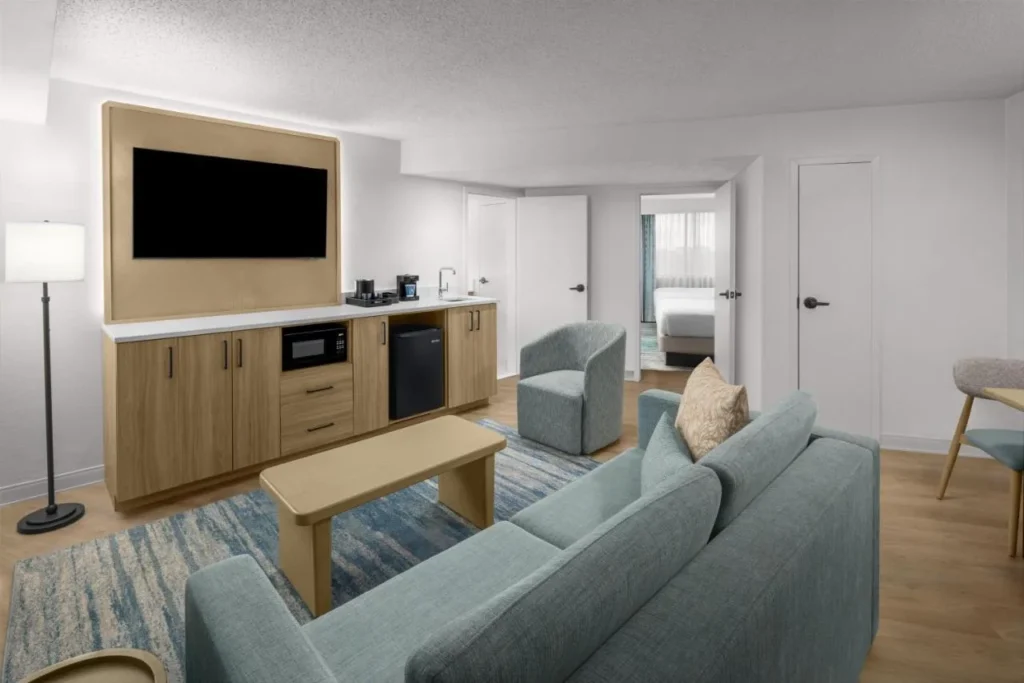 Sala de estar renovada en suite con sof&aacute;, bar y dormitorio en Embassy Suites ICON Park
