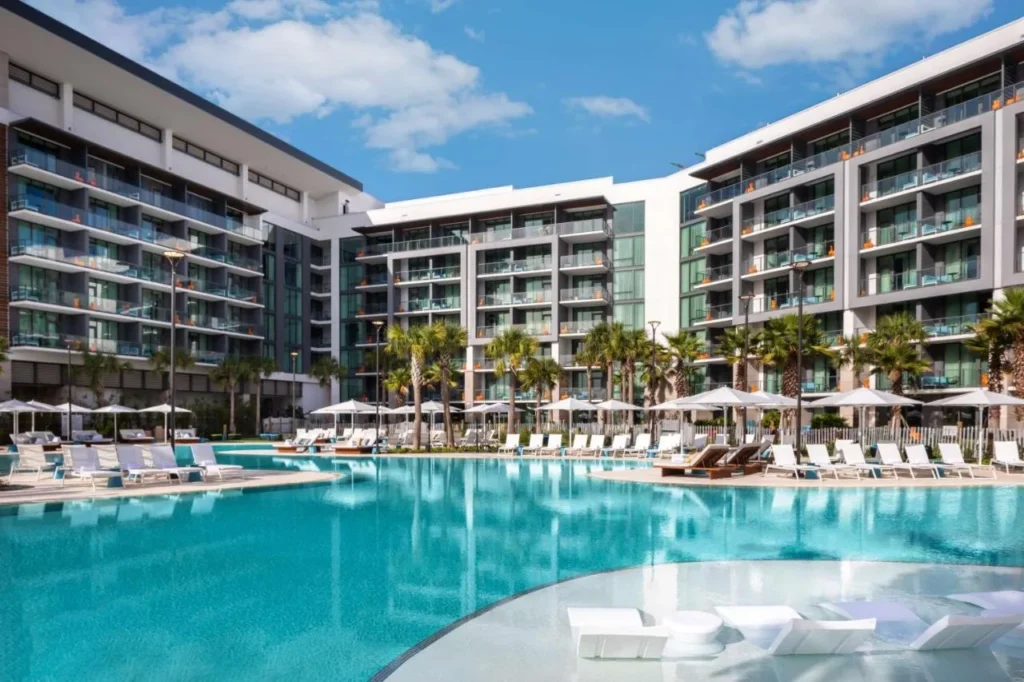 Piscina del complejo con tumbonas en el agua rodeadas de alas con balconied en Conrad Orlando