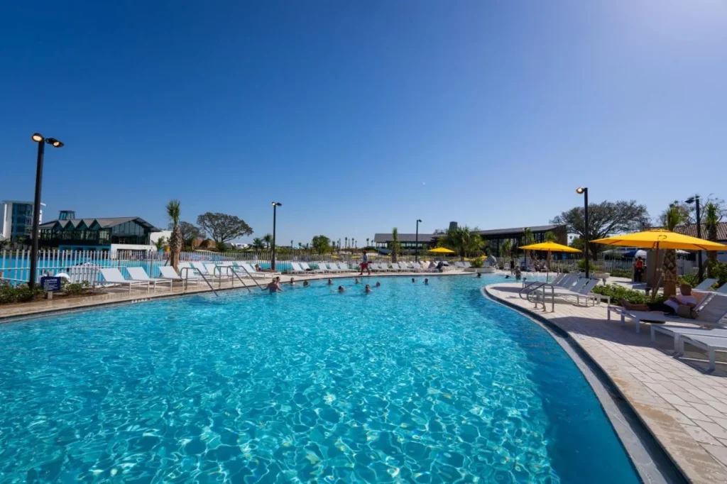Resort pool with loungers and yellow umbrellas beside Evermore Bay at Evermore Orlando Resort