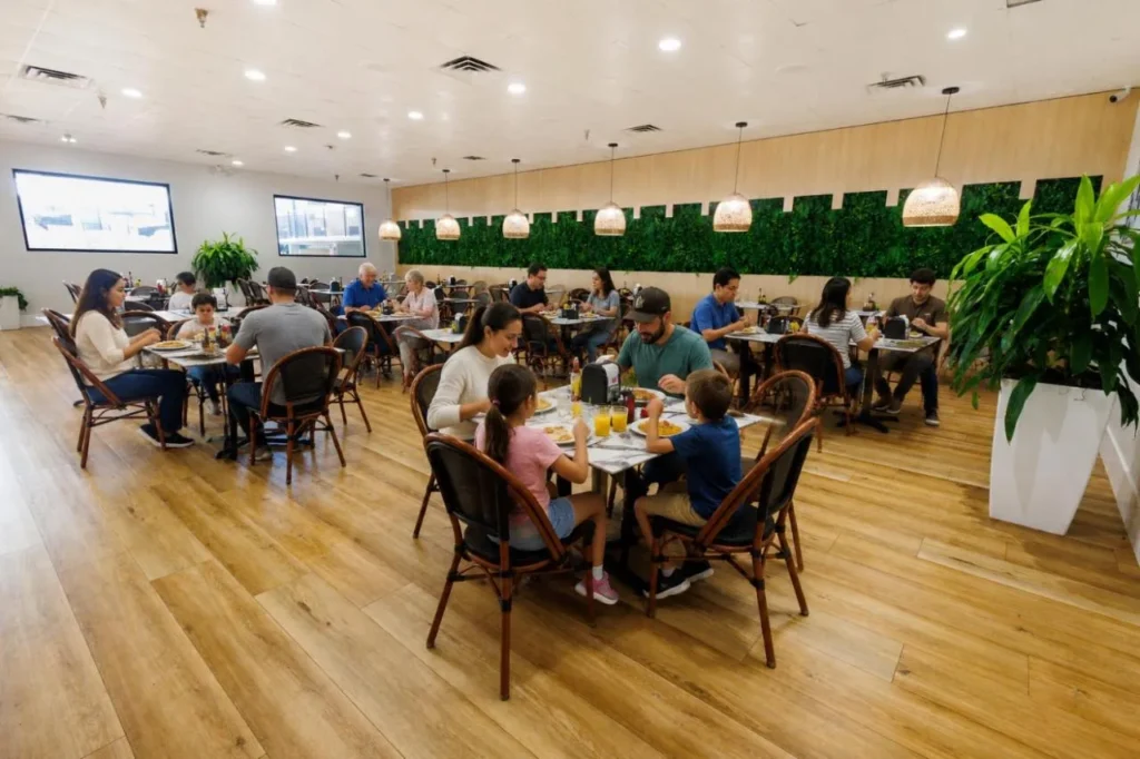 Restaurante comedor con una pared de planta verde y familias en las mesas en CoCo Key Hotel