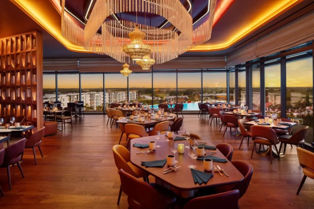 Restaurant dining room with floor-to-ceiling windows at sunset at Conrad Orlando