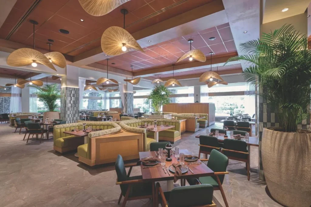 Comedor del restaurante con reservados verdes y l&aacute;mparas colgantes tejidas en Loews Royal Pacific Resort