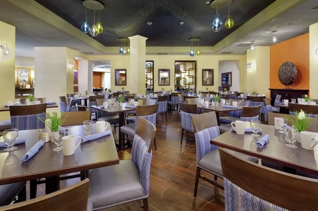 Restaurante comedor con mesas fijas y luces colgantes de colores en DoubleTree by Hilton Orlando Downtown