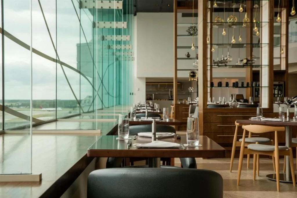 Restaurant tables beside a tall glass wall overlooking the airfield at Hyatt Regency Orlando International Airport