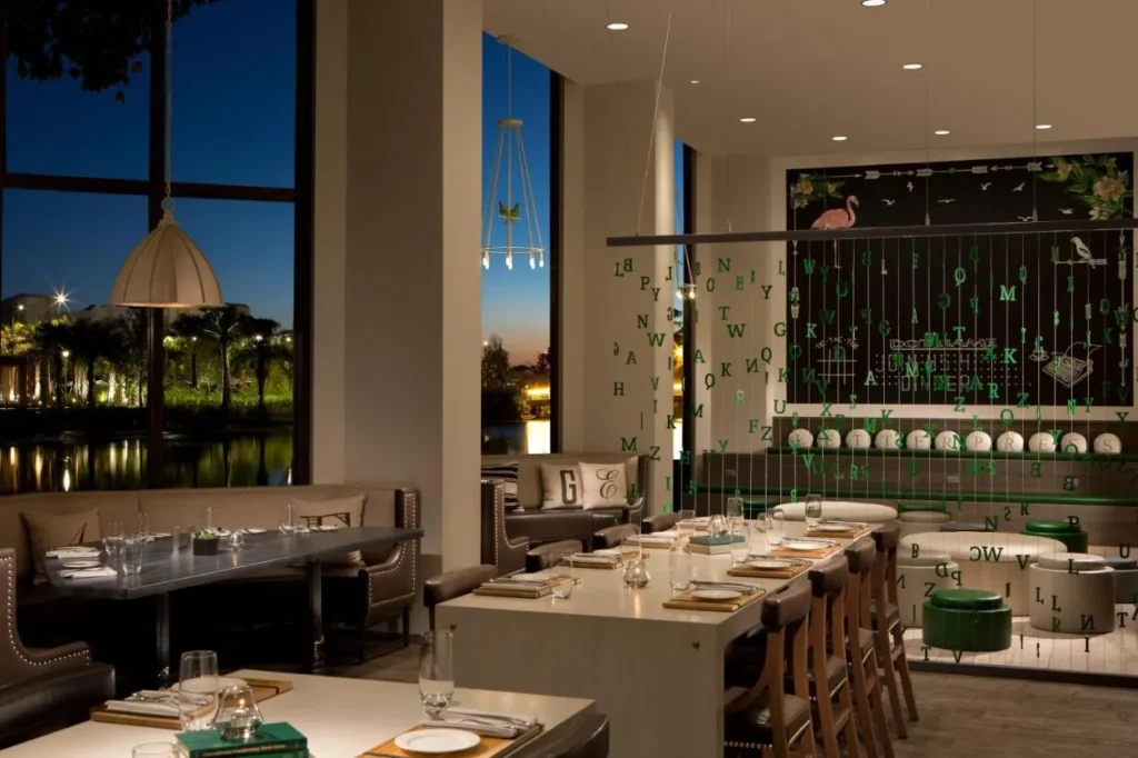 Restaurant with lakeside windows and long tables at dusk at Hilton Orlando Buena Vista Palace