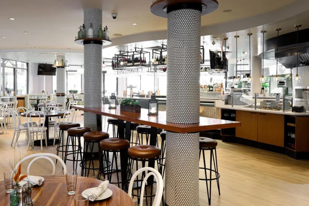 Restaurant with tiled columns, high bar tables and an open kitchen at Meliá Orlando Celebration