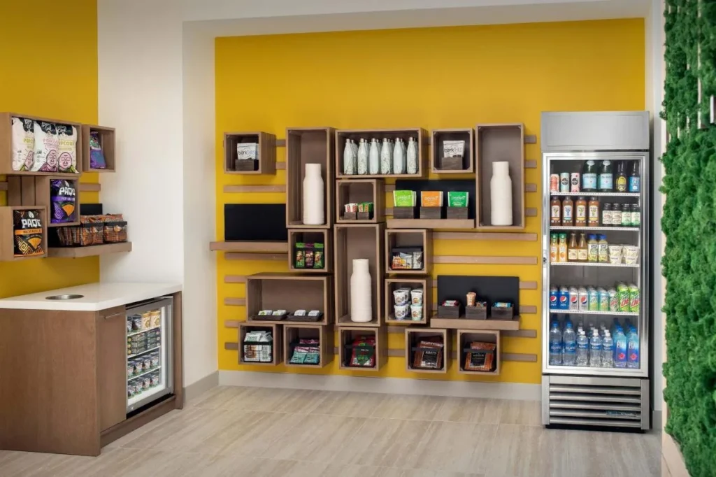 Restaurar el mercado con bocadillos en estantes de pared amarillos y un enfriador de bebidas, Element Orlando
