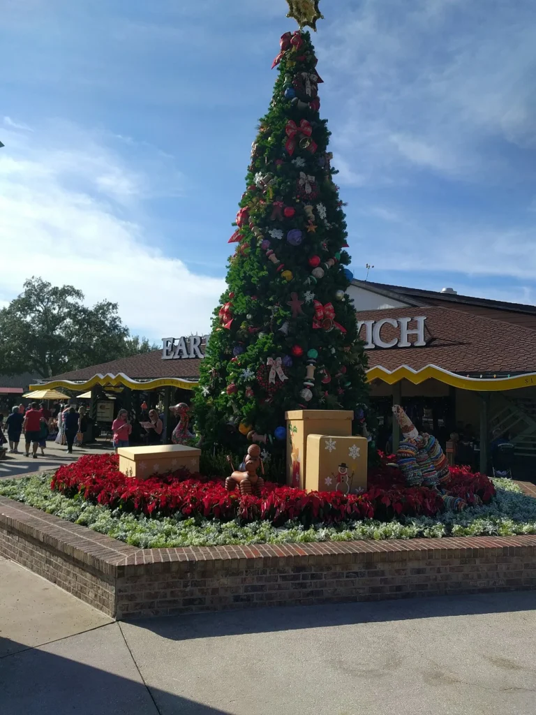 Ribboned Christmas tree above red poinsettias in the Marketplace at Disney Springs