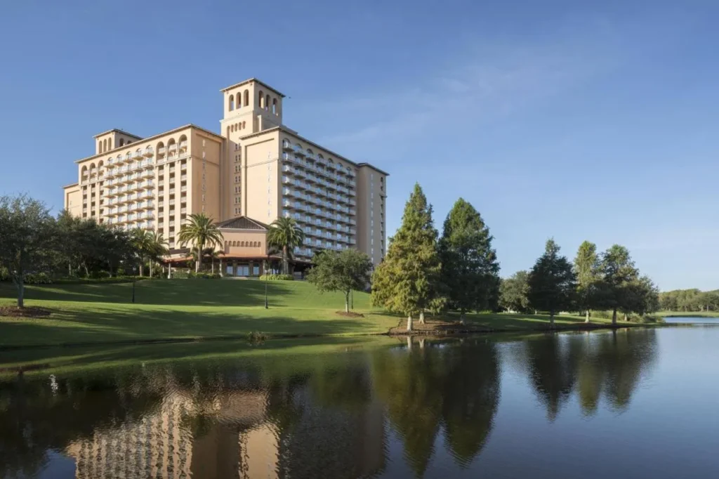 Torre Ritz-Carlton Orlando Grande Lakes que se eleva sobre un césped inclinado y un lago tranquilo