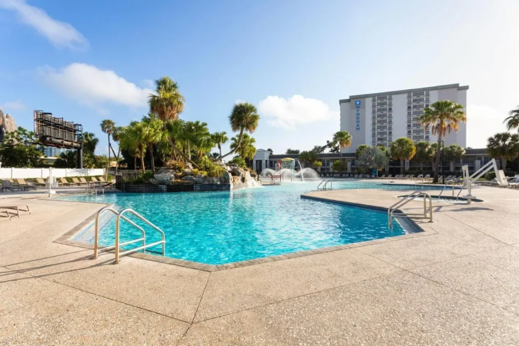 Piscina bordeada de rocas con fuentes y la torre Wyndham detrás en Wyndham I-Drive Avanti Resort