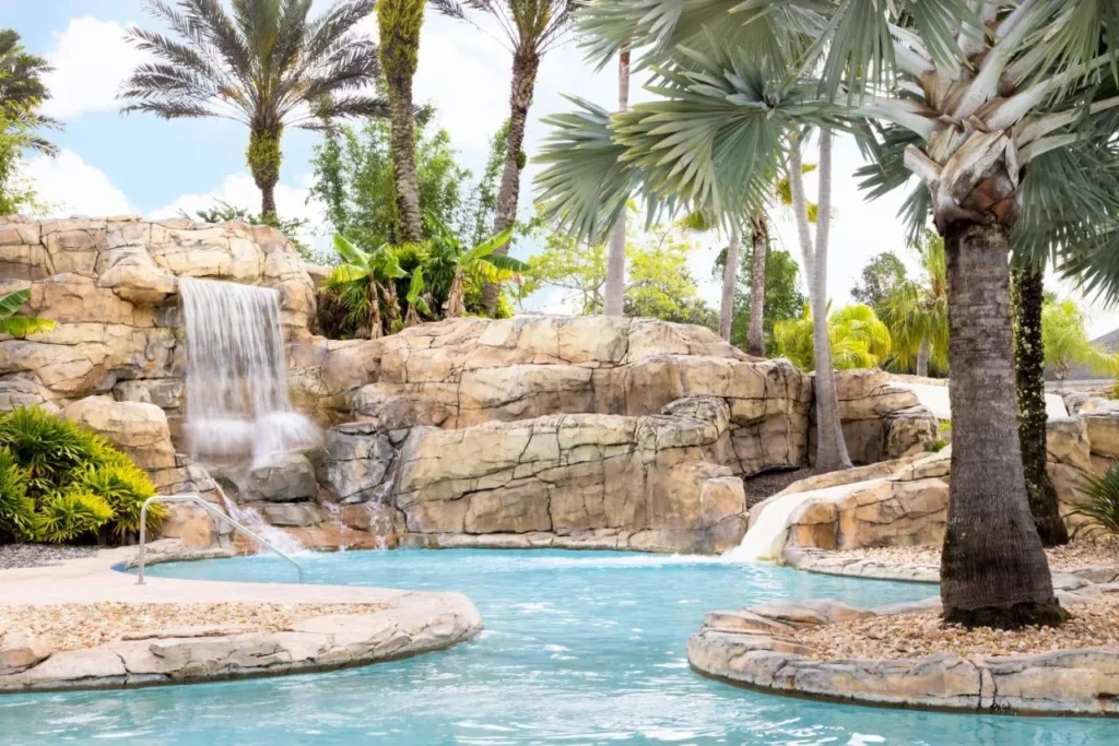 Cascada de roca y palmeras junto a una piscina sinuosa en Reunion Resort & Golf Club