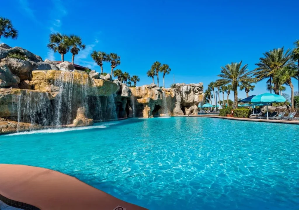 Cascadas de roca que se vierten en la piscina de la laguna turquesa en Hyatt Regency Grand Cypress bajo las palmeras