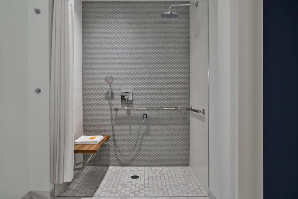 Roll-in shower with a fold-down bench and grab bars at Walt Disney World Swan Reserve