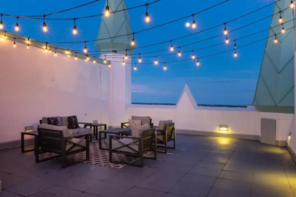 Rooftop lounge with string lights, outdoor sofas and green spires at Castle Hotel Orlando