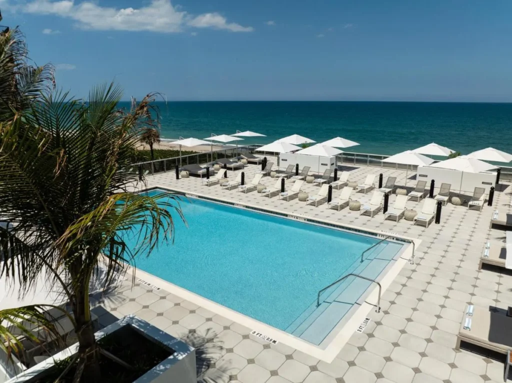 Rooftop saline pool with loungers and umbrellas overlooking the ocean at Element Melbourne Oceanfront