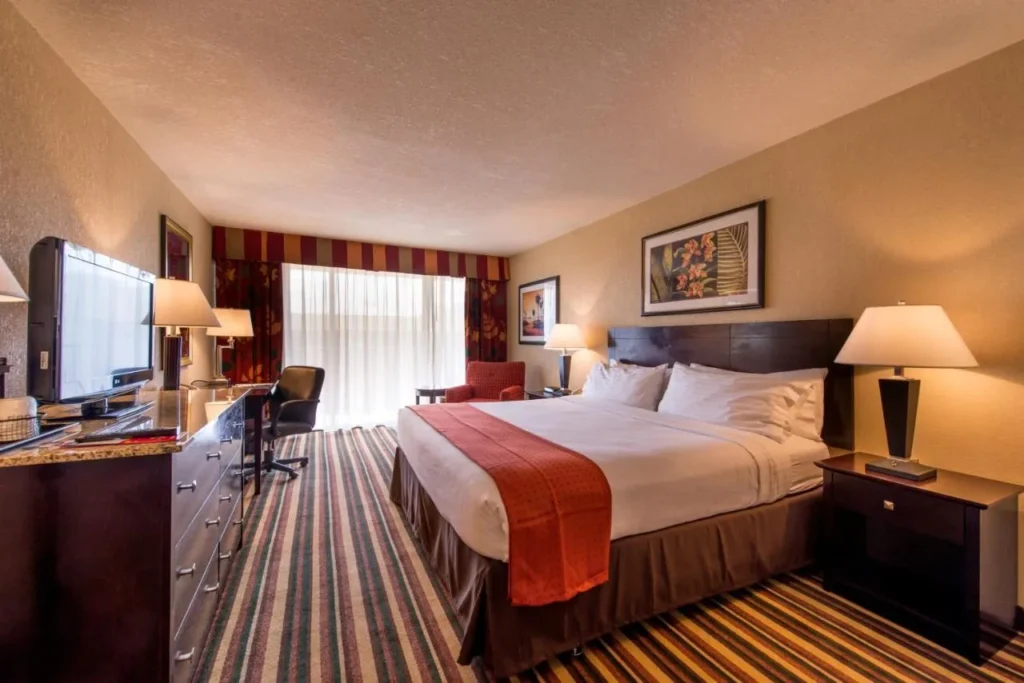 Room with a large bed, dresser and red bed runner at Holiday Inn Orlando SW Celebration