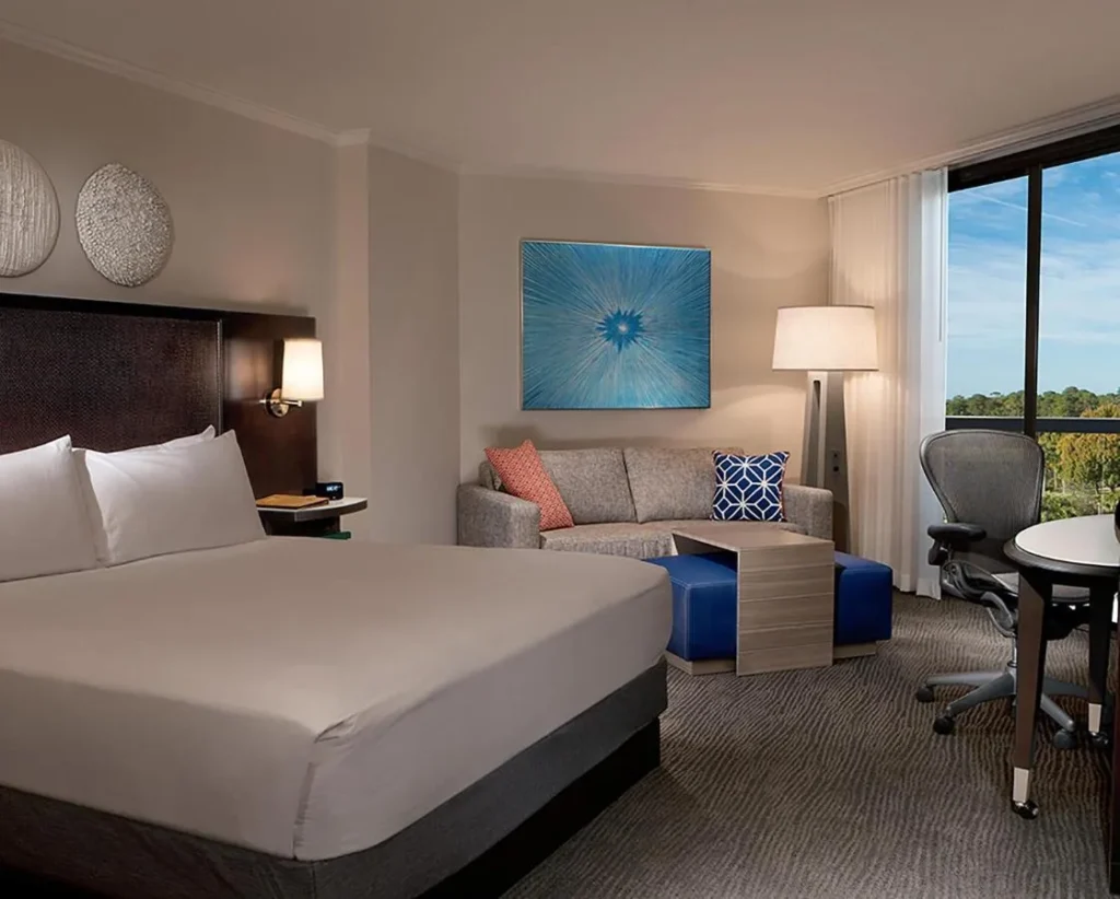 Room with a large bed, sofa and tree-view window at Hilton Orlando Buena Vista Palace