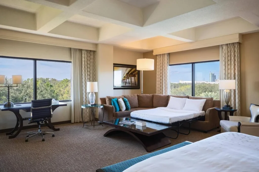 Habitación con sofá cama, escritorio y ventanas amplias en Renaissance Orlando at SeaWorld