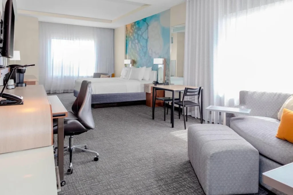 Room with bed, sofa, small table and work desk at Courtyard DeLand Historic Downtown