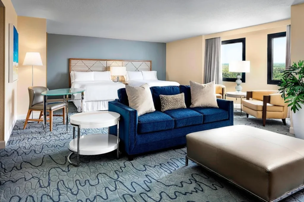 Room with two beds, a blue sofa and an ottoman at Walt Disney World Dolphin
