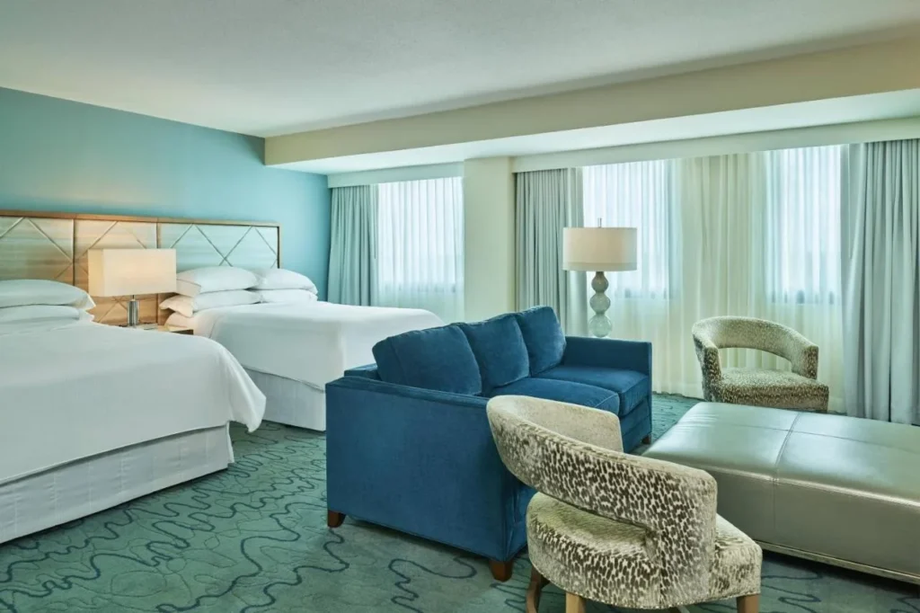 Room with two beds, a blue sofa and an upholstered ottoman at Walt Disney World Dolphin