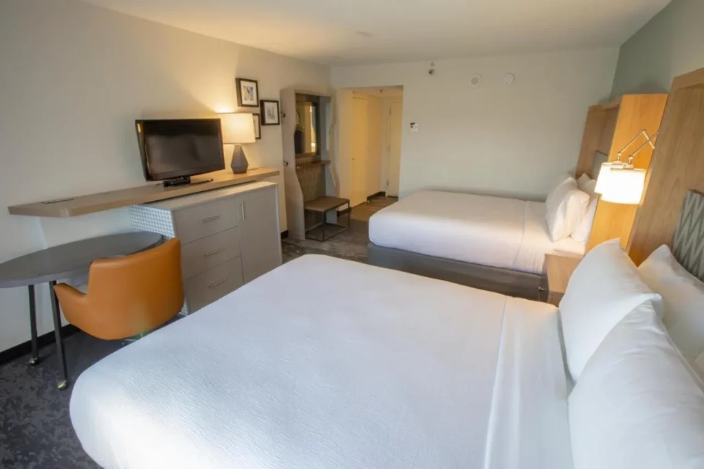Habitaci&oacute;n con dos camas, un escritorio y una silla naranja en el Holiday Inn Orlando International Airport