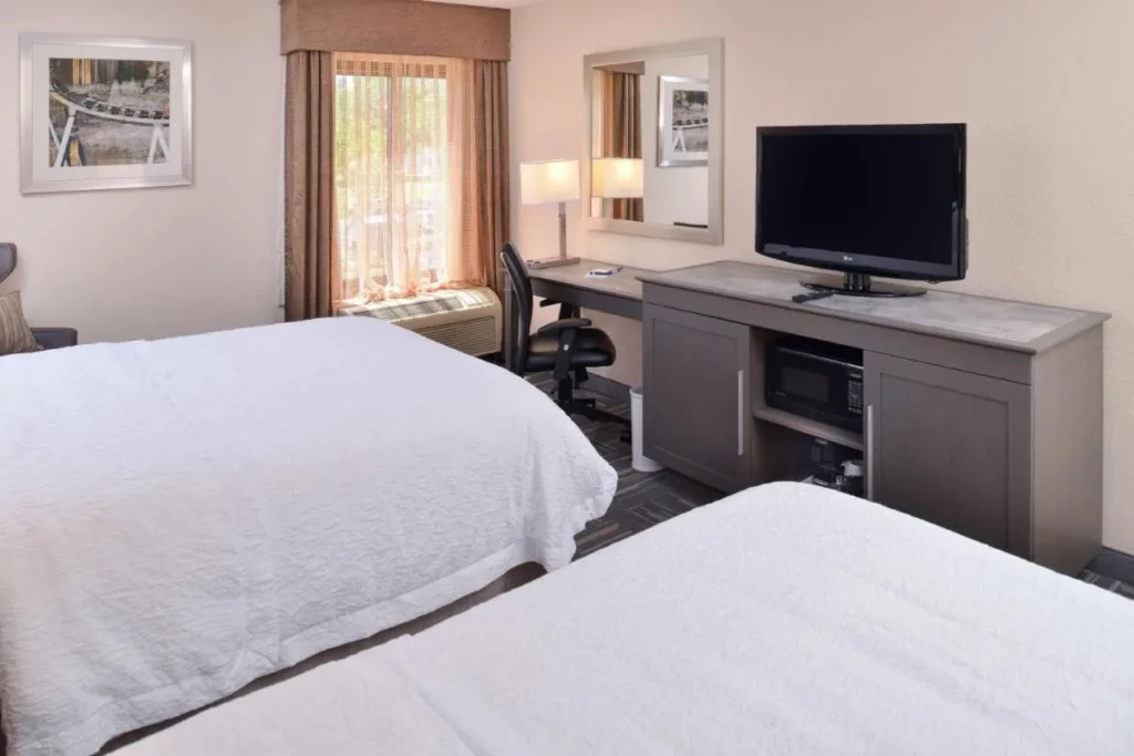 Room with two beds, a desk, TV and microwave at Hampton Inn Closest to Universal Orlando