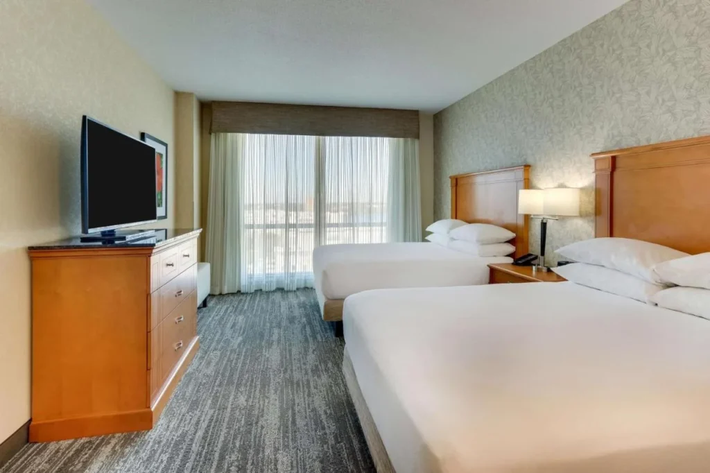Room with two beds, a dresser and TV at Drury Inn & Suites near Universal
