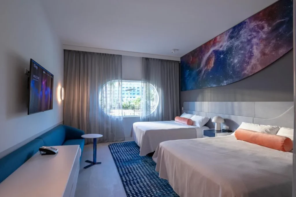 Habitaci&oacute;n con dos camas, un mural de galaxia y una ventana ovalada en Stella Nova Resort