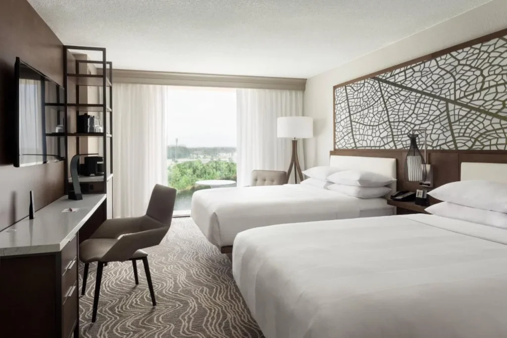 Habitaci&oacute;n con dos camas, una pared de cabecera con patr&oacute;n de hoja y una ventana en el Marriott Orlando Airport Lakeside