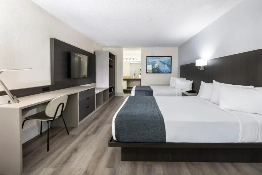 Room with two beds, a long desk and wood-look floors at Avanti International Resort