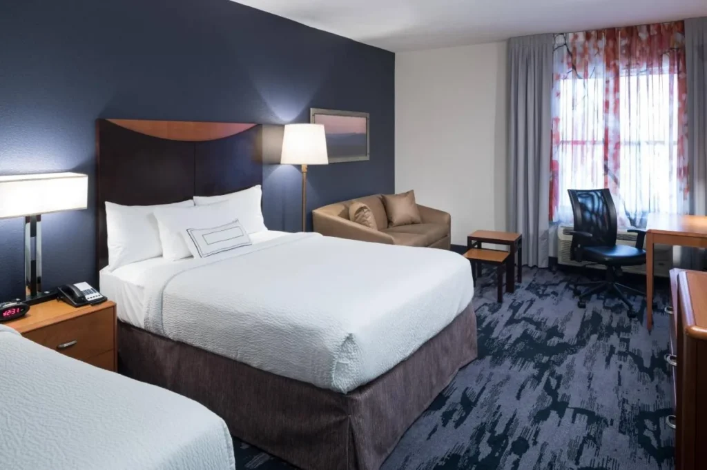 Habitación con dos camas, un sofá cama y escritorio en Fairfield Inn & Suites Orlando at SeaWorld