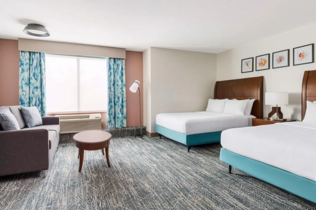 Habitación con dos camas, sofá y mesa redonda en Hilton Garden Inn Orlando at SeaWorld