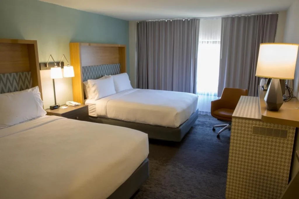 Habitaci&oacute;n con dos camas, un sill&oacute;n y un escritorio en Holiday Inn Orlando International Airport