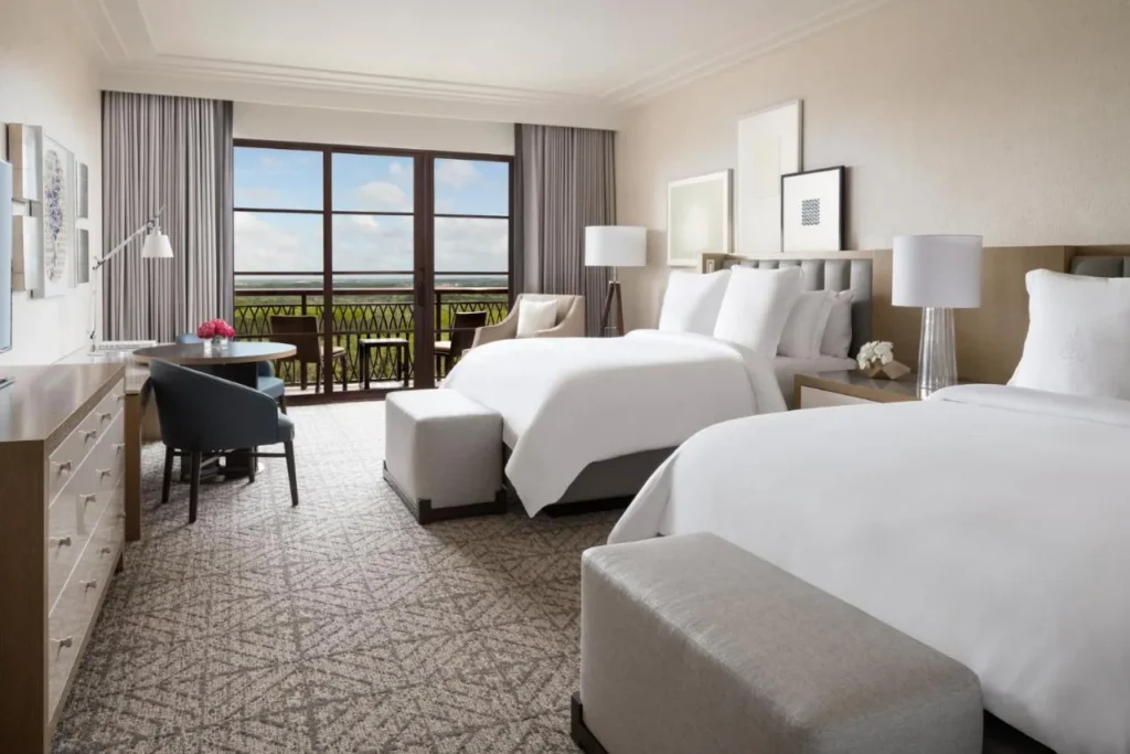 Room with two beds and a balcony overlooking treetops at Four Seasons Resort Orlando