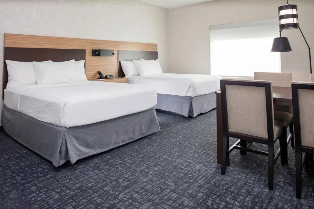 Habitaci&oacute;n con dos camas y una mesa de comedor en TownePlace Suites Orlando Airport