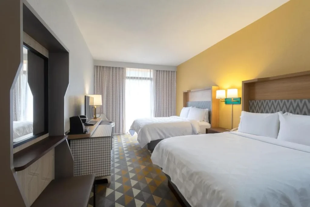 Habitación con dos camas y una pared de acento amarillo en Holiday Inn & Suites Orlando SW
