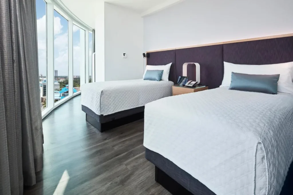 Room with two beds and floor-to-ceiling curved windows overlooking the resort, Universal's Aventura Hotel