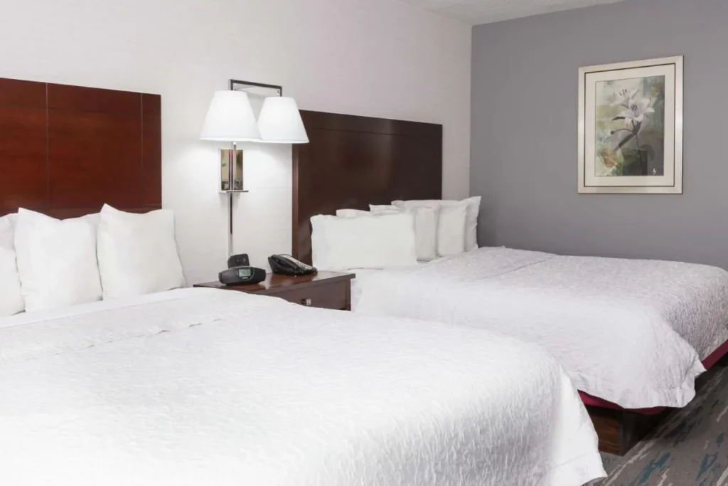 Habitaci&oacute;n con dos camas y ropa de cama blanca en Hampton Inn & Suites Orlando Airport
