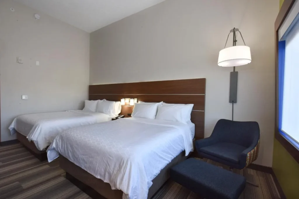 Habitaci&oacute;n con dos camas, sill&oacute;n y otomana en Holiday Inn Express & Suites Orlando Southeast