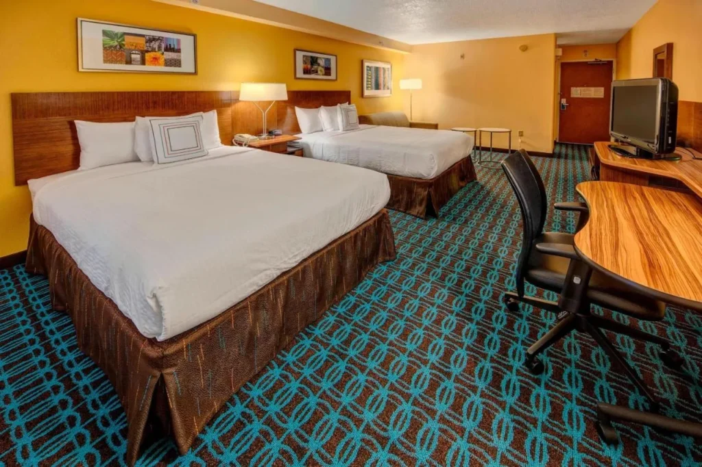 Room with two beds, curved desk and sofa at Fairfield Inn & Suites Near Universal