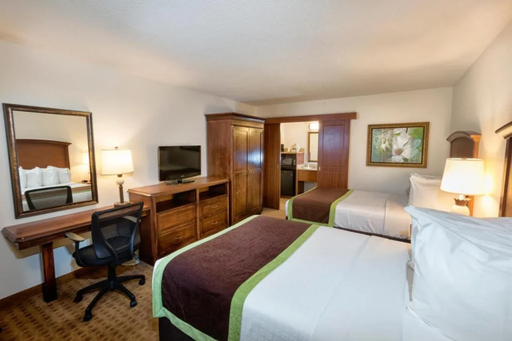 Room with two beds, desk, TV and armoire at Rosen Inn Lake Buena Vista