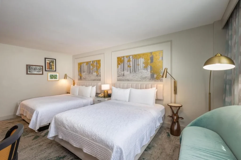 Room with two beds, gold forest artwork and a teal sofa at Castle Hotel Orlando