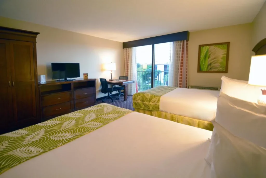 Habitación con dos camas, colchas verdes y escritorio en Rosen Inn Closest to Universal