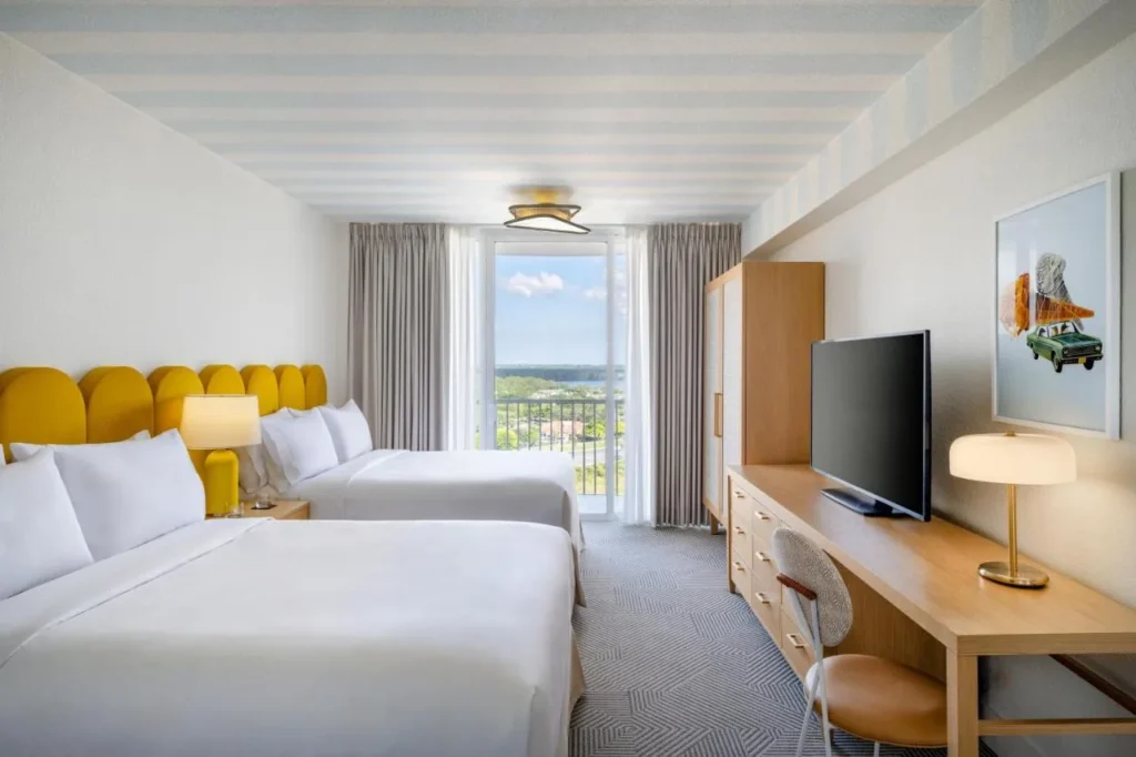 Room with two beds, scalloped yellow headboards and a balcony at Renaissance Orlando Resort